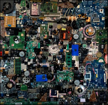 A dense, intricate collage composed of various electronic components, circuit boards, and mechanical parts forming an abstract, symmetrical pattern.