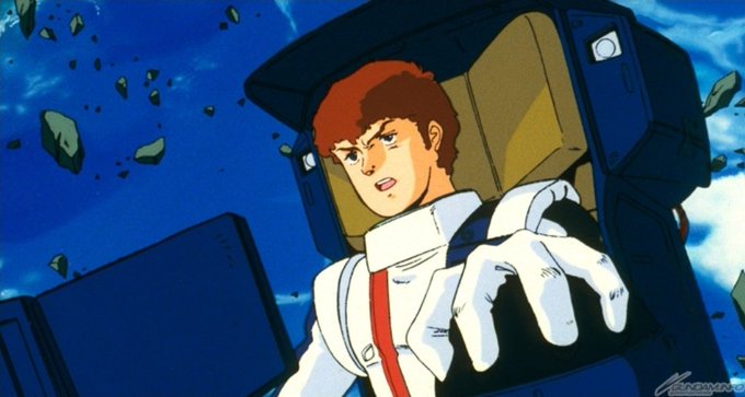 An anime still showing a young man with reddish-brown hair wearing a white and blue pilot suit, sitting in a cockpit with debris floating outside against a blue sky.