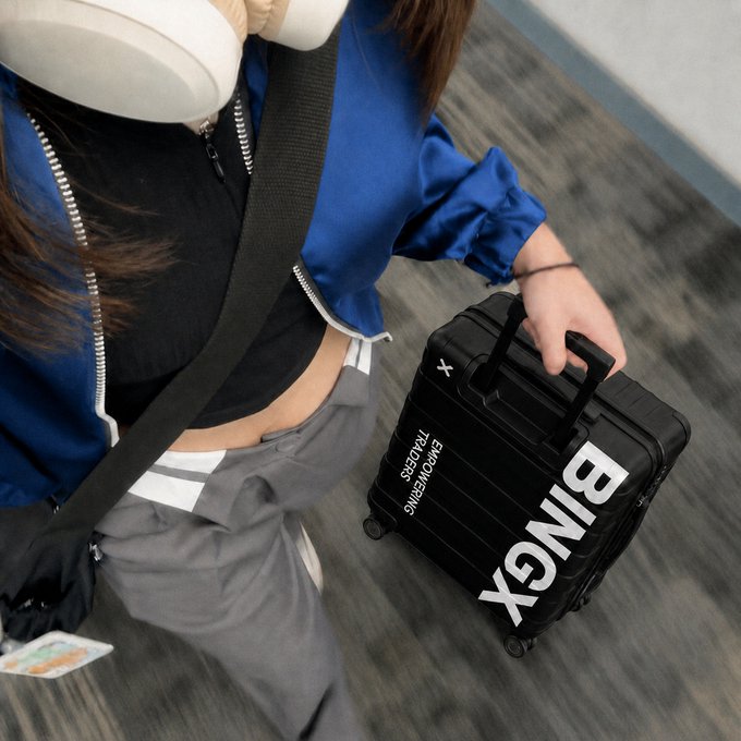A traveler walks through an airport pulling a sleek black carry-on suitcase emblazoned with "BINGX" and "EMPOWERING TRADERS," visually reinforcing the post's message of taking one's edge on the go.