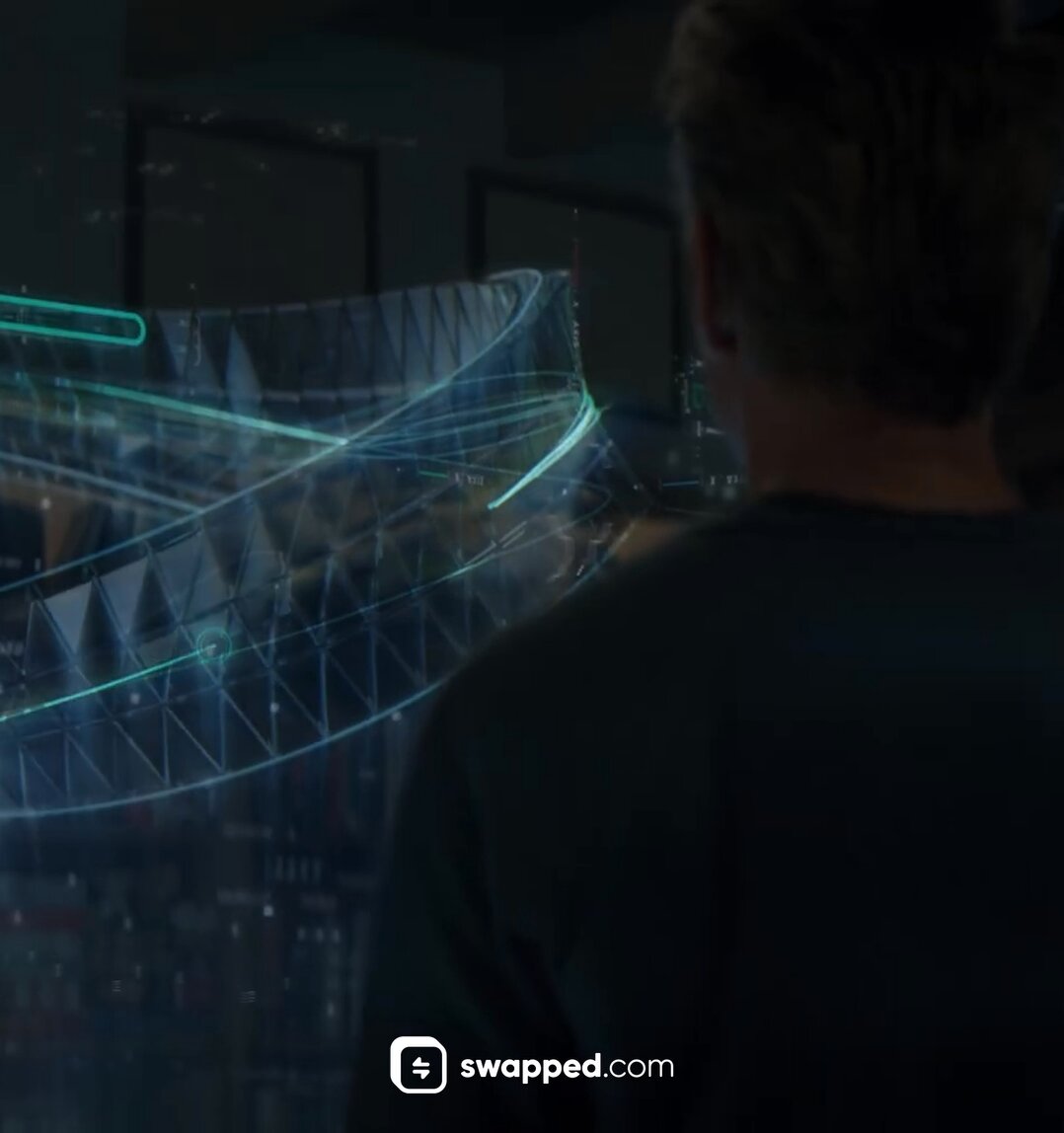The image shows a man wearing a black shirt, looking at a computer screen that displays an abstract design of a building with blue lines. The background appears blurry, suggesting that the focus is on the man's face and the computer screen. There are also some text elements in the image, including "@swappedcom" and "When you want to buy Bitcoin". This could be related to the post about buying Bitcoins or discussing the abstract design displayed on the computer screen.