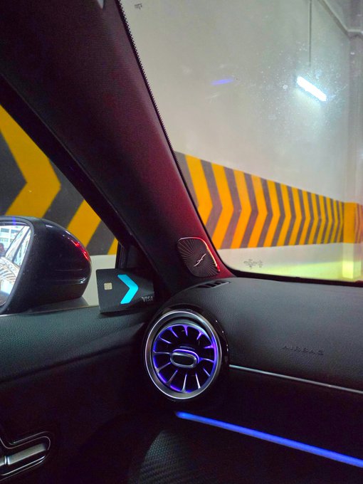 A view from inside a car parked in a tunnel, featuring a circular air vent with blue ambient lighting, a side mirror reflecting headlights, and yellow-and-black chevron warning stripes on the wall ahead—underscoring the post's "there's only one way" as the road forward leads into a tunnel exit.