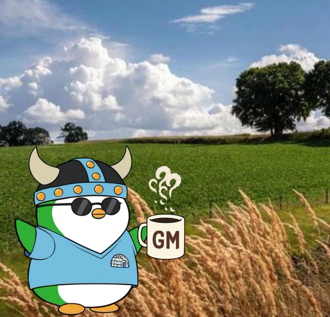 A cartoon penguin wearing a viking helmet and sunglasses holds a coffee mug labeled "GM" while standing in a green field.
