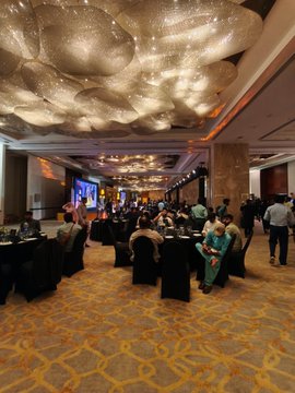 An elegant banquet hall featuring ornate cloud-shaped chandeliers, with guests seated at round tables in a formal event setting.