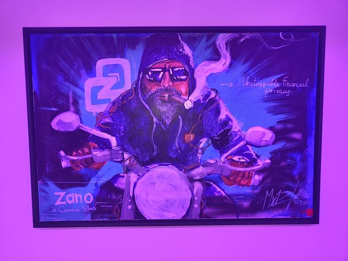 A purple-toned painting depicts a bearded biker smoking a cigar on a motorcycle, featuring the Zano logo, the text 'Zano is Coming Soon,' and 'Unstoppable Financial Privacy.'