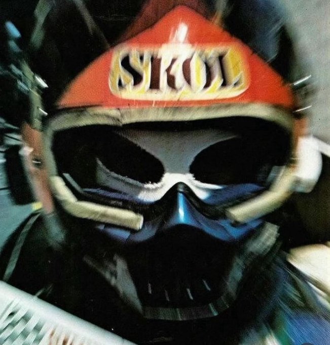 A close-up photo of a person wearing a Strol-branded motocross helmet with ski goggles, creating a stylized, edgy portrait.