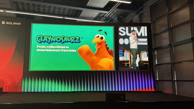 A speaker presents on stage at a Solana-sponsored event, with a large screen displaying a 'CLAYNOSAURZ' presentation slide about transitioning from collectibles to entertainment franchise.