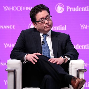 A man in a dark suit, blue tie and glasses sits on a panel stage with "YAHOO! FINANCE" and "Prudential" logos on a purple backdrop, appearing to be at a financial conference. The image matches the caption about Tom Lee, the well-known Fundstrat strategist, discussing the market sell-off as a buying opportunity at what appears to be a Yahoo Finance event.