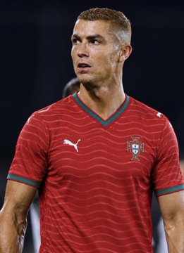 Cristiano Ronaldo is pictured wearing a red Portugal national team jersey with green trim.