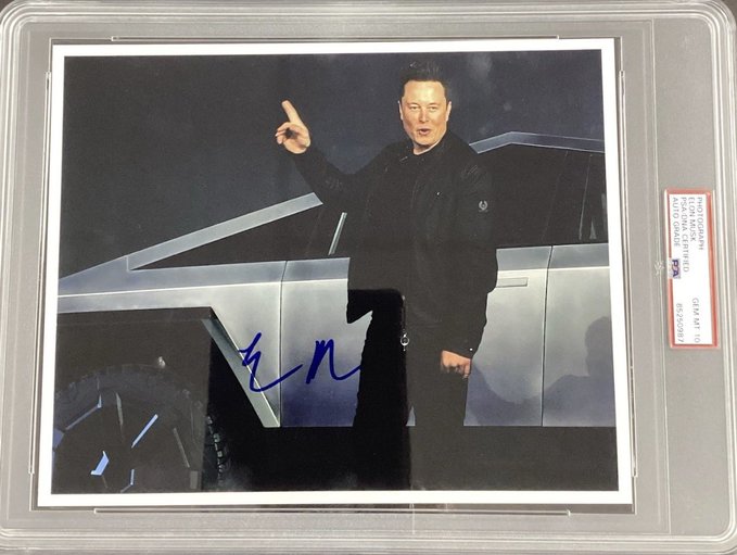 A PSA-graded autographed photo of Elon Musk pointing upward, standing in front of a Tesla Cybertruck.