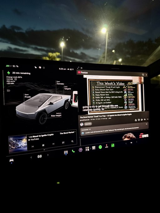 A Tesla vehicle touchscreen display showing a Cybertruck image with 20 minutes of charging remaining at 90 kW, alongside a YouTube video titled 'This Week's Video' viewed at night.