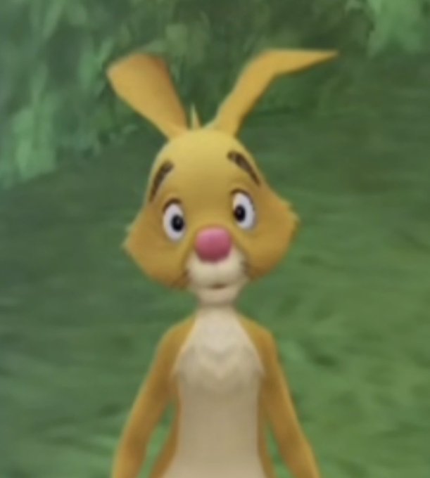 A 3D animated cartoon rabbit character with yellow fur, a pink nose, and large expressive eyes standing in a green grassy environment.
