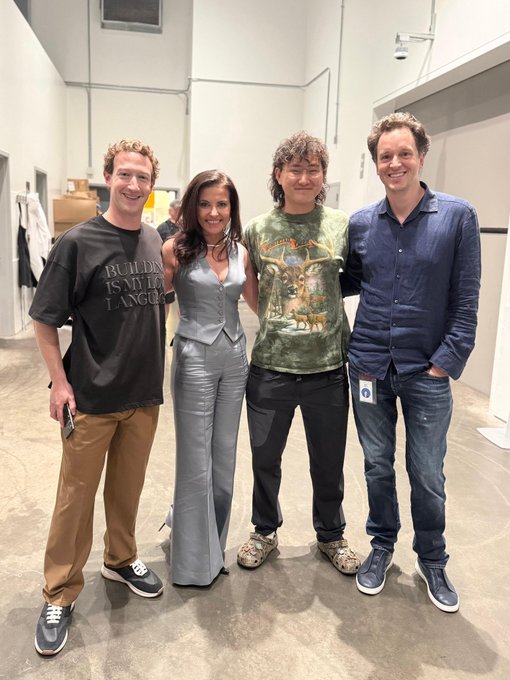Four people posing together indoors, including Mark Zuckerberg on the right, with one wearing a 'Building is my love language' t-shirt.
