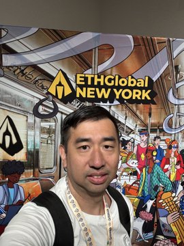The image features a man wearing a backpack, standing next to a poster or sign that reads "ETHGlobal New York". He appears to be posing for a photo, possibly at an event related to the hackathon. The background of the image is filled with various people and objects, suggesting a lively atmosphere. The text on the poster indicates that the event was held in New York City over the weekend.
