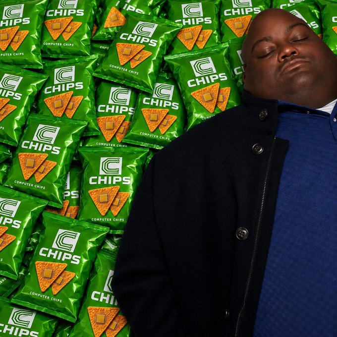 A humorous edited image showing a large man leaning against a massive pile of green 'C Chips' (Computer Chips) snack bags.