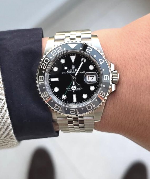 A close-up of a Rolex GMT-Master II watch with a black dial and bezel worn on a wrist.