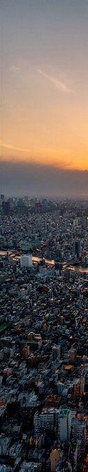 This vertical panoramic image captures Tokyo at sunset, showcasing a sprawling cityscape with countless illuminated buildings stretching toward the horizon, where a river winds through the urban expanse under a sky transitioning from deep blue to warm orange and amber hues. The image perfectly complements the caption "QT with your Sunset Art," offering a breathtaking view of nature's evening palette over Tokyo—a perfect setting for quiet reflection or sharing with someone special.