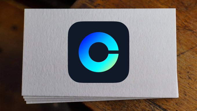 A stack of white business cards resting on a wooden surface, featuring a dark rounded square logo with a stylized gradient blue 'C' shape in the center.