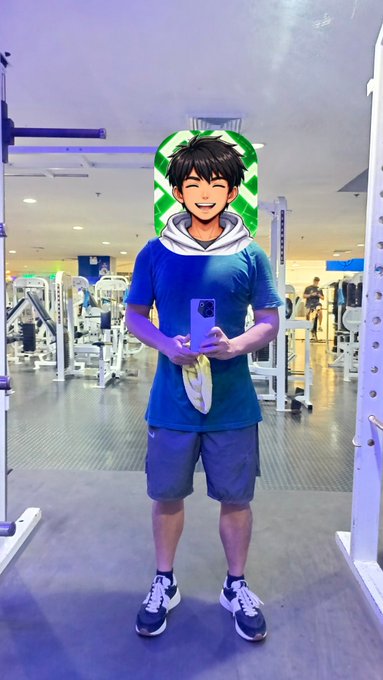 A photo of a young man taking a mirror selfie in a gym using a purple phone, with an anime-style cartoon avatar sticker of his face edited over his head.