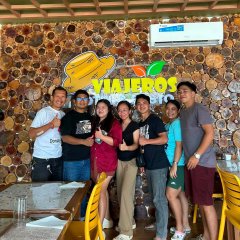 A group of eight people pose together at a wooden-themed restaurant featuring decorative log slices on the wall and a sign reading "VIAJEROS," celebrating Richard's praise at the Philippines meetup mentioned in PulseChain's Weekly Monster Thread #62.