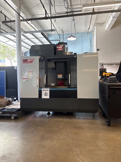 A large Haas VF-2SS Super Speed CNC milling machine inside an industrial workshop with concrete floors and exposed ceiling infrastructure.