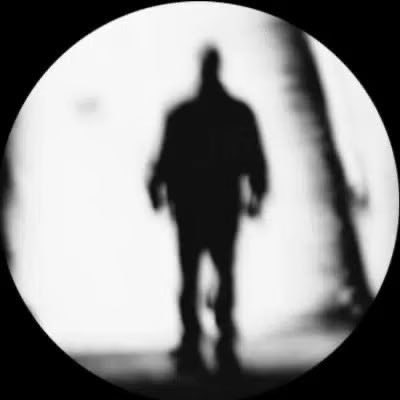 A blurry, black-and-white circular image shows the dark silhouette of a hooded figure walking forward, fittingly evoking the mysterious "Shadow" branding referenced in the post about @_Shadow36 announcing a launch.