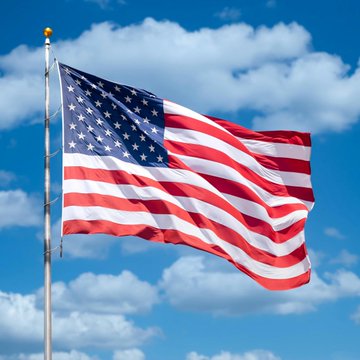The image shows the American flag waving against a bright blue sky with scattered white clouds. This patriotic symbol relates to the post by representing the U.S. economy and Treasury market, as rising yields on American government bonds and anticipated Federal Reserve rate hikes reflect concerns about the nation's financial outlook.