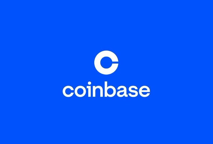 The image shows the Coinbase logo, featuring a white circular emblem above the "coinbase" wordmark on a solid blue background. This branding relates to the announcement of Coinbase expanding its platform to allow eligible U.S. retail users direct access to IPO allocations, beginning with Oura, marking its deeper entry into traditional finance and primary markets.