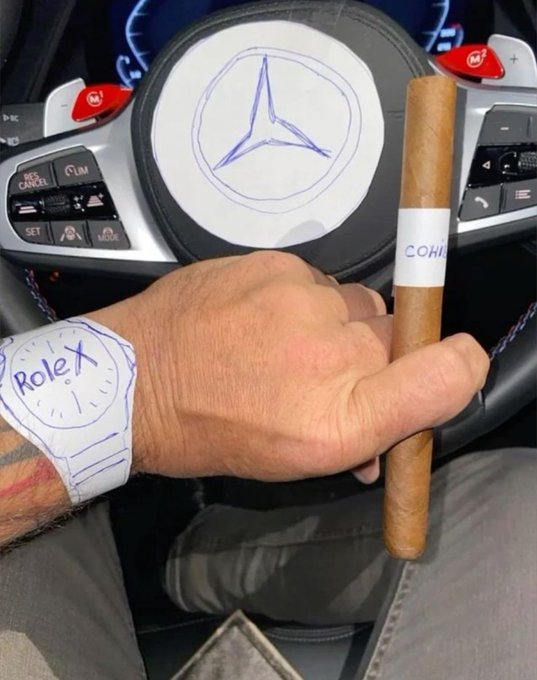 A hand rests on the steering wheel of a Mercedes-Benz vehicle (logo hand-drawn in blue marker on the airbag cover) while holding a Cohiba cigar, with a paper "Rolex" watch also drawn in blue marker taped to the wrist—mocking the appearance of luxury wealth despite the crude, hand-made imitations, all humorously credited to crypto profits.