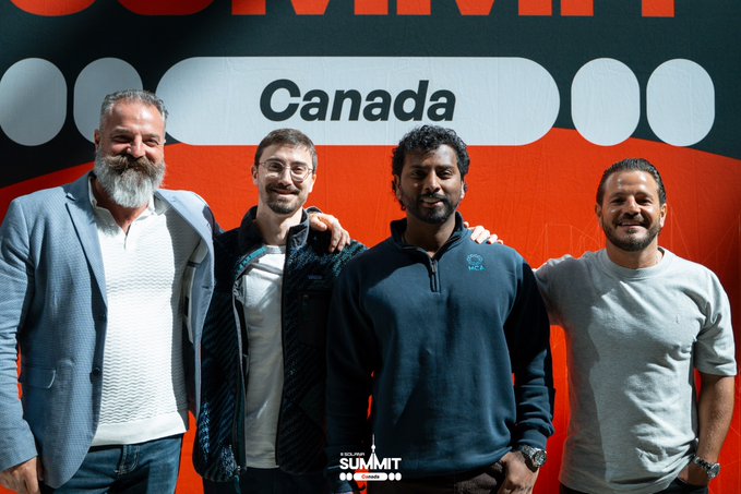 Four men pose together in front of a red backdrop displaying the word 'Canada'; a 'SUMMIT' logo with 'TORONTO 2026' and 'SEPTEMBER 24-26' is visible at the bottom center of the image.