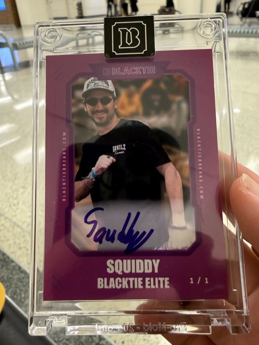 A hand holding a 'BLACKTIE' trading card featuring 'SQUIDDY' with an autograph, showing a person in sunglasses and a 'SQUIDZ' shirt, marked as 'BLACKTIE ELITE 1/1'.