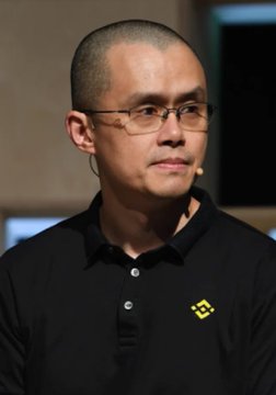 A man with a shaved head and glasses, wearing a black polo shirt featuring the Binance logo, speaks into a headset microphone during what appears to be a conference or interview. The image relates to the post as it depicts a Binance representative, likely Changpeng Zhao (CZ), discussing the company's thwarted efforts to secure an EU license due to intervention from European Central Bank President Christine Lagarde.