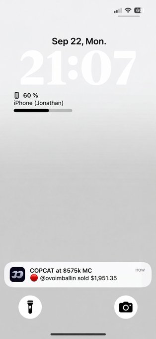 An iPhone lock screen dated 'Sep 22, Mon.' showing time 21:07, 60% battery for iPhone (Jonathan), and a notification 'COPCAT at $575k MC @ovoimballin sold $1,951.35'.