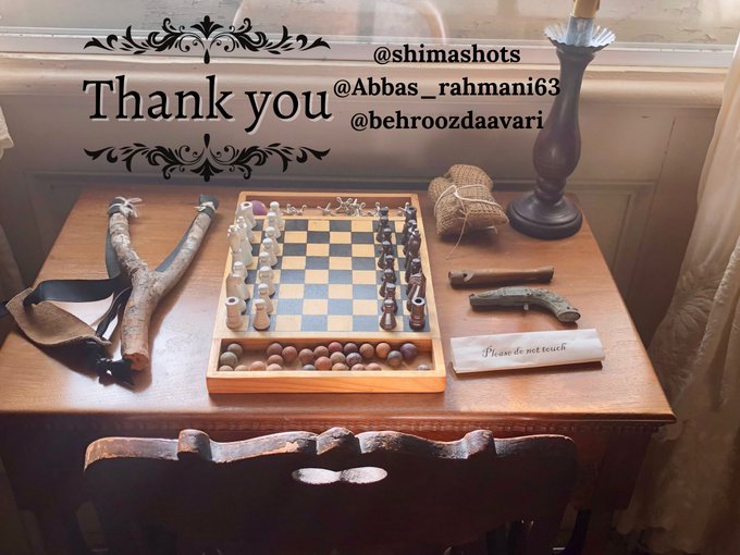 A photograph of a wooden table with a chess set, a slingshot, a knife, and a pistol, with overlaid text 'Thank you' and handles '@shimashots', '@Abbas_rahmani63', and '@behroozdaavari'.