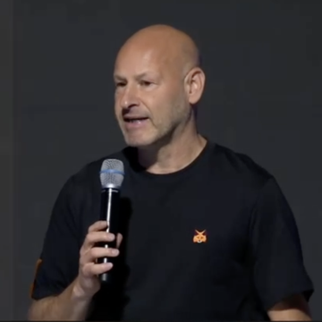 A bald man in a black t-shirt with a small orange logo speaks into a microphone, identified by the accompanying post as ConsenSys CEO Joe Lubin, pictured during his remarks at Korea Blockchain Week 2026 regarding MetaMask's (MASK) native token plans.