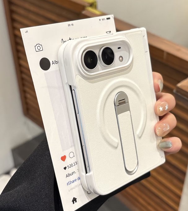 A person's hand with decorated nails holds a white textured phone case with a circular magnetic ring and stand, displayed in front of its packaging showing a social media interface with likes, comments, and album details.