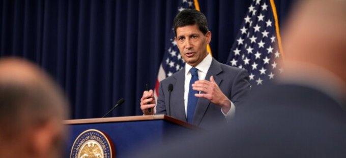 A man in a suit speaking at a podium bearing the US Department of State seal, gesturing while American flags hang in the background.