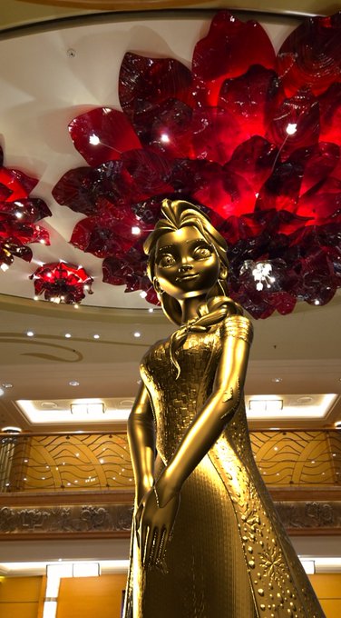 A golden Elsa statue stands beneath an elaborate red glass chandelier aboard the Disney Wonder. The image connects to the post’s Disney Cruise and *Frozen* theme, with the hashtag #VeVe and ticker $OMI also referenced.