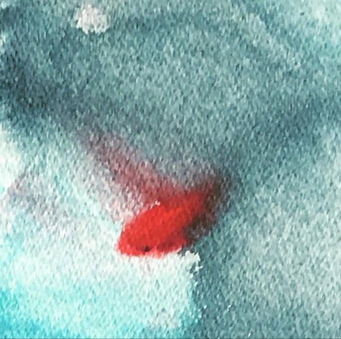 A blurry close-up of a goldfish with a bright red head swimming in blue-tinted water.