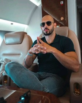 Andrew Tate, wearing sunglasses and a black polo, sits confidently with crossed legs inside a private jet, fingers steepled in a poised gesture. The post promotes the presale of his crypto project "The Real World" ($TRW), with the image's luxury setting reinforcing the message of wealth and exclusivity.