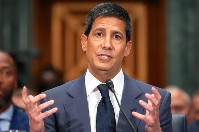 A man in a navy suit and tie speaks emphatically into a microphone, gesturing with both hands in what appears to be a formal government hearing setting. The image likely illustrates Federal Reserve policy discussions, relating to the post's commentary about the Fed quietly injecting liquidity back into the financial system after ending Quantitative Tightening—a shift that could soon impact asset prices.