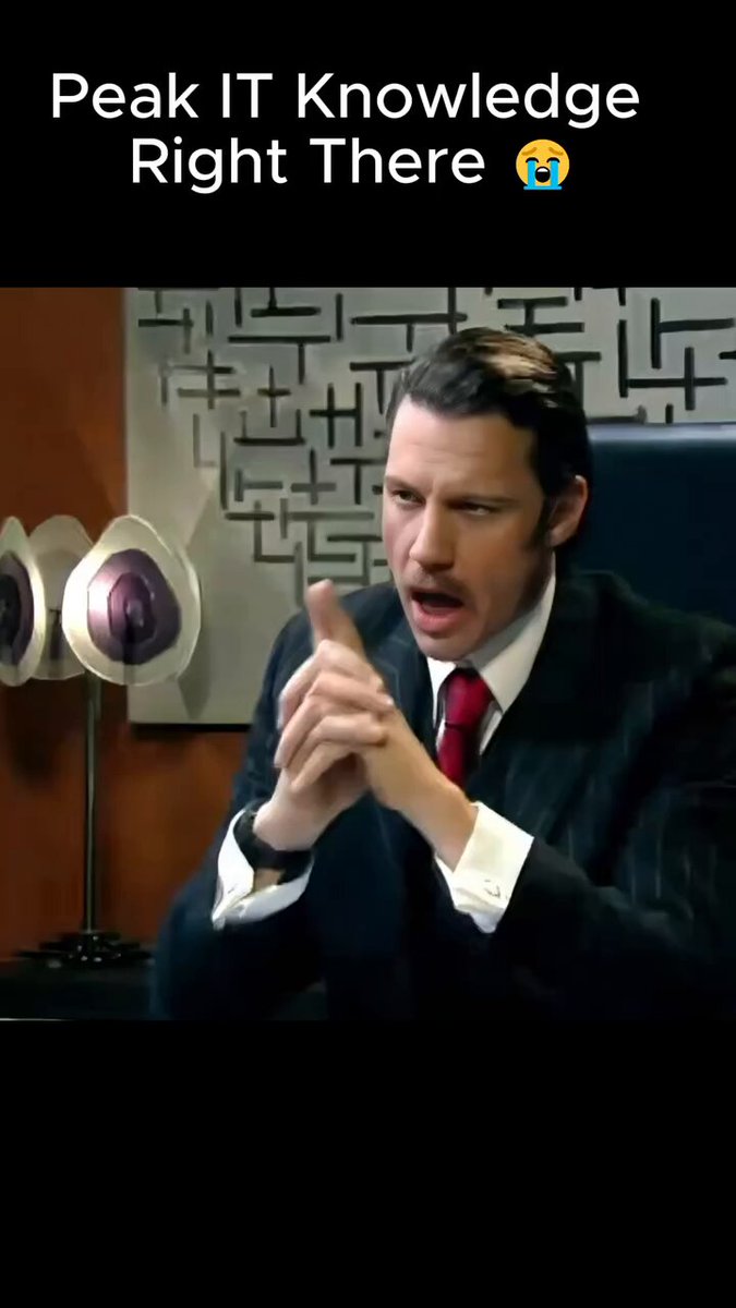 iced tea with a straw, a black lamp, and a red tie are present on the desk, accompanied by a man in a suit holding his hands together.
