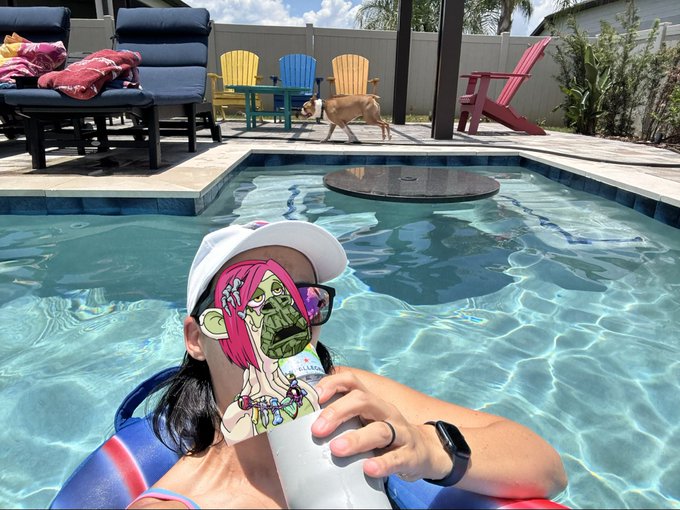 A woman relaxing by a pool holding a drink with a digital character sticker overlay, and a dog in the background.