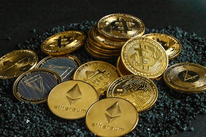 A collection of physical cryptocurrency coins, prominently featuring "Bitcoin" and "ethereum" engravings, rests on a dark, textured surface. The image illustrates the context of South Korea's ongoing debate over its proposed 22% tax on crypto gains, which has gained traction due to a petition exceeding 50,000 signatures.