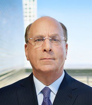 A professional headshot of an older man wearing glasses and a navy suit against a blue background.