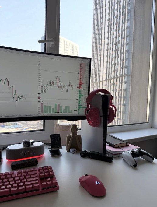 A sleek desk setup featuring a Samsung monitor displaying a trading chart with candlesticks and volume bars, accompanied by red Logitech headphones on a stand, a red mechanical keyboard, and a Logitech mouse, all set against a city view. The chart and post caption referencing "$SOL" suggest the workspace belongs to a crypto trader monitoring Solana's price action.