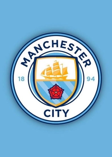 The image displays the Manchester City FC crest featuring a golden sailing ship, the founding year "1894," and the words "MANCHESTER CITY" on a light blue background. This relates to the post highlighting Manchester City's aggressive transfer spending, contrasting with Manchester United's modest net spend this window.