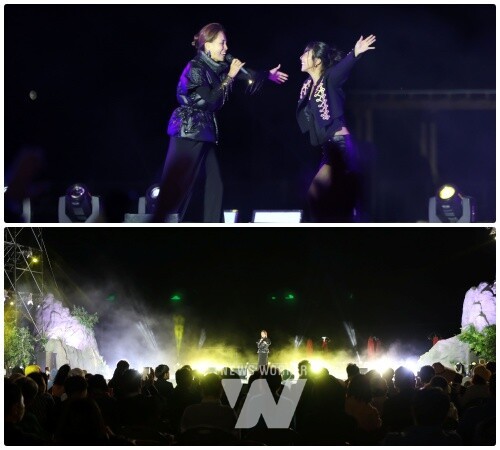 A composite image showing a concert scene: the top half captures two performers singing together on stage, while the bottom half shows a wider view of the stage with the "W" logo and a member named "JENNIFER WONG" visible, along with an audience in the foreground.