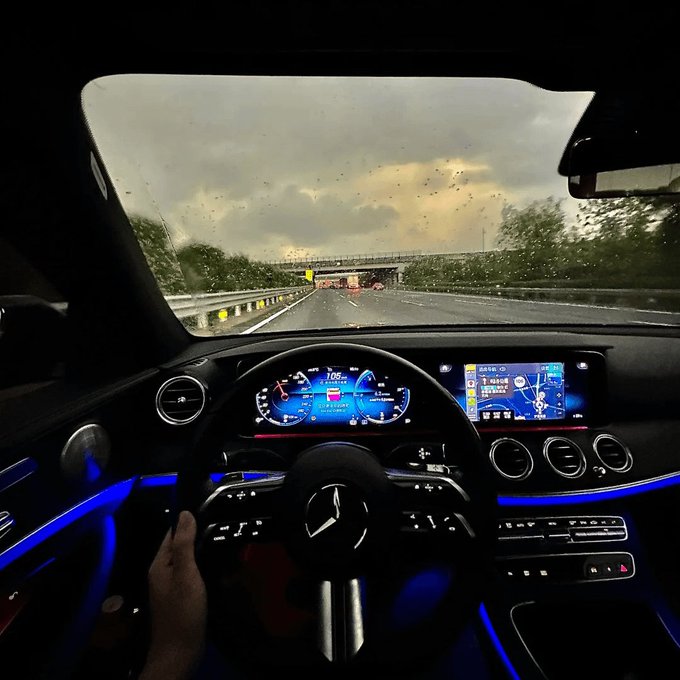 A driver's POV from inside a Mercedes-Benz (visible by the logo on the steering wheel) traveling at 106 mph on a highway under rainy skies, with dashboard displays showing "Crypto Twitter" navigation—a visual metaphor for "driving fast" through volatile crypto markets without proper caution or learning, mirroring the post's warning about reckless crypto trading habits.
