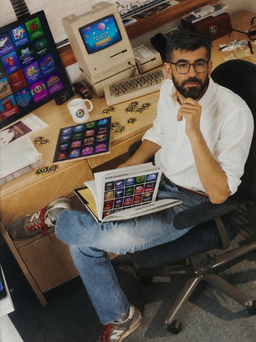 A bearded man in glasses sits at a retro Mac desktop reviewing a "Game Collection" booklet, surrounded by branded Boss Program promotional materials and digital screens. The image aligns with the post by depicting the creator behind the rapidly growing Boss Program, which reportedly delivers $300+ average weekly earnings.
