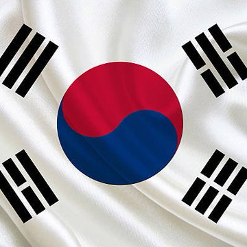The South Korean flag waves prominently in the image, symbolizing the nation's renewed crypto trading surge, with Upbit's 24-hour volume soaring 273% to $1.84 billion and XRP leading the charge at $418.9 million, followed by gains on rival exchange Bithumb.